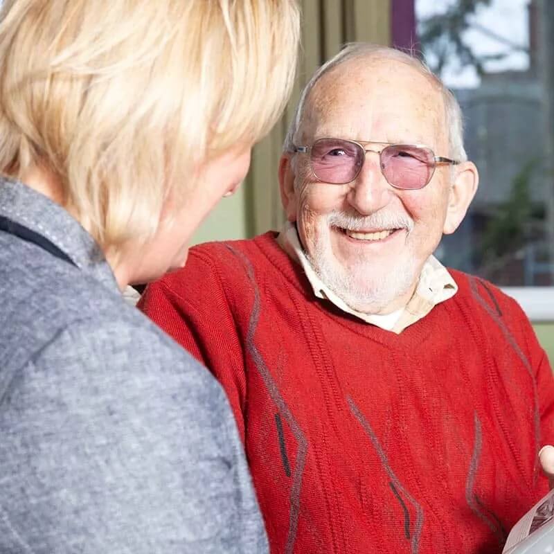 A man is talking to a woman in a nursing home