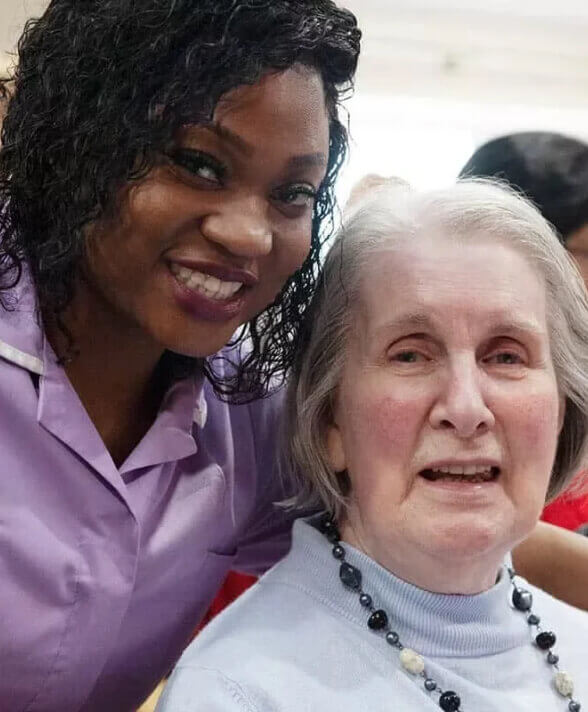 A caretaker poses for a photo with an elderly woman