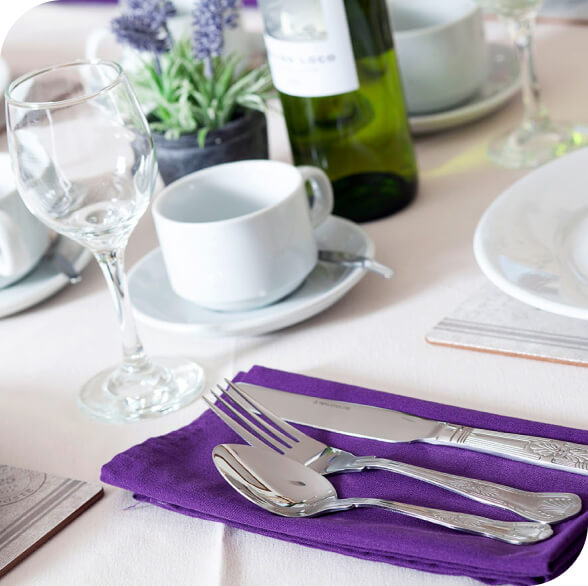 A table setting with a purple napkin and silverware at a care home in Epsom