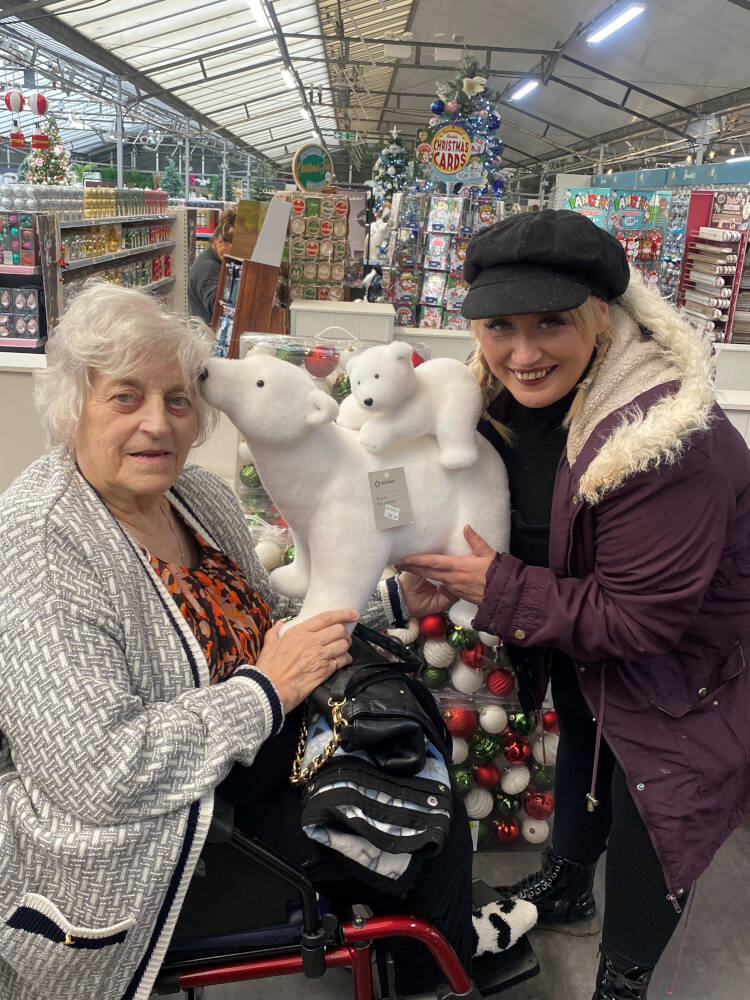 A woman is gifing a polar bear soft toy to an old woman