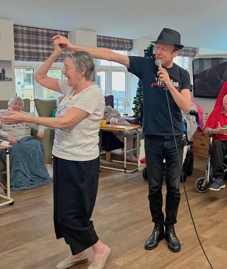 A man in a hat and a woman dance together at Oaklands